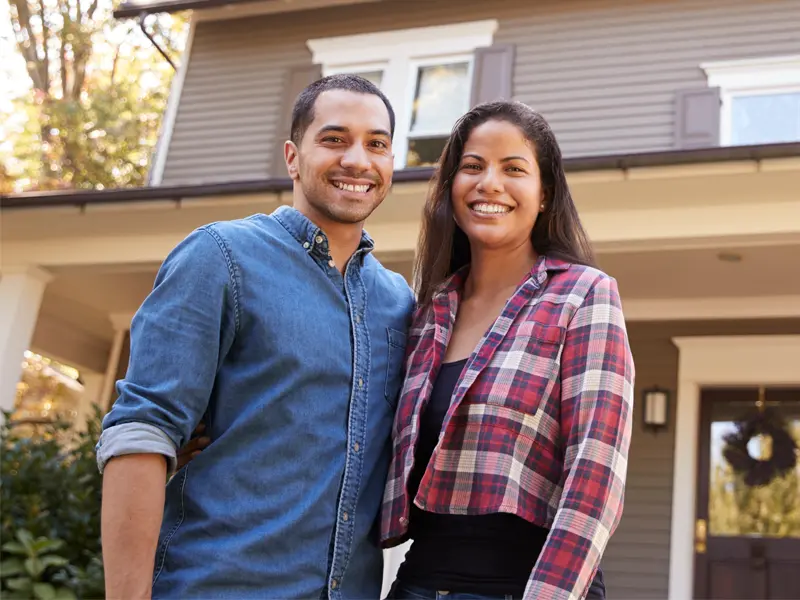 A couple smiling in front of their home after Concord 24/7 fire damage restoration by Best Cleanup